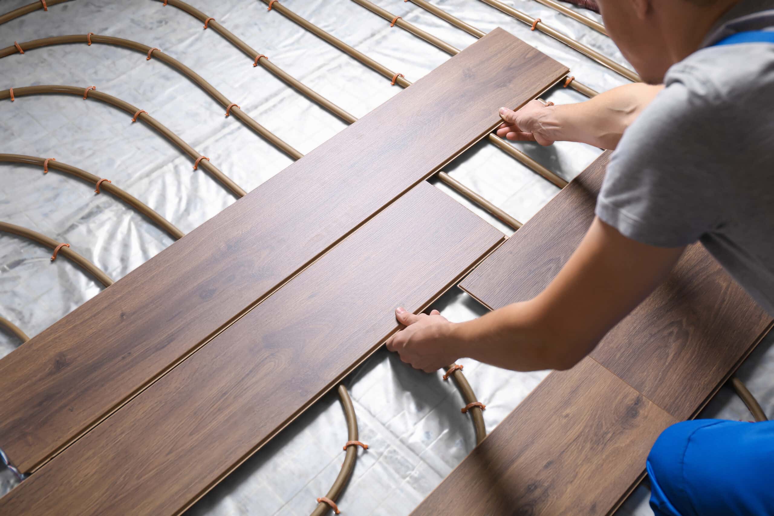 worker installing new wooden laminate over underfloor heating sy worker installing new wooden laminate over underfloor heating sy