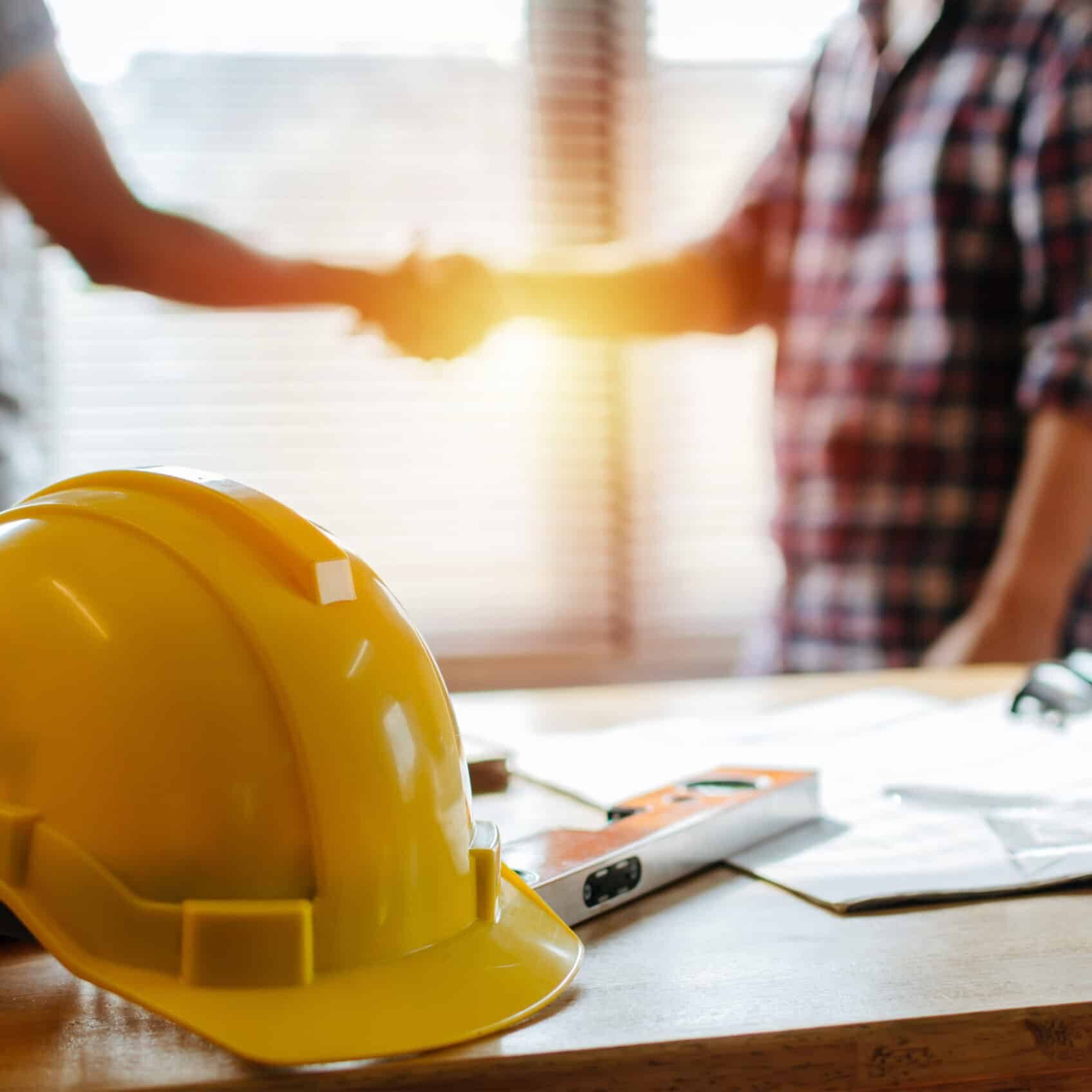 yellow safety helmet on workplace desk with construction worker